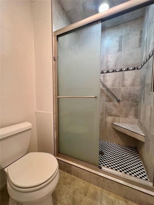 bathroom featuring a shower with shower door and toilet