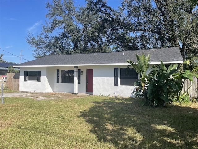 ranch-style house with stucco siding, fence, roof with shingles, and a front lawn