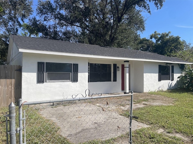 single story home featuring a fenced front yard, stucco siding, and roof with shingles