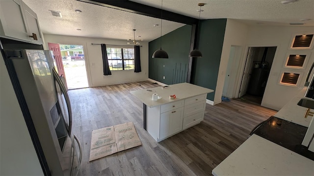 kitchen featuring stainless steel refrigerator with ice dispenser, open floor plan, light wood-type flooring, and a textured ceiling