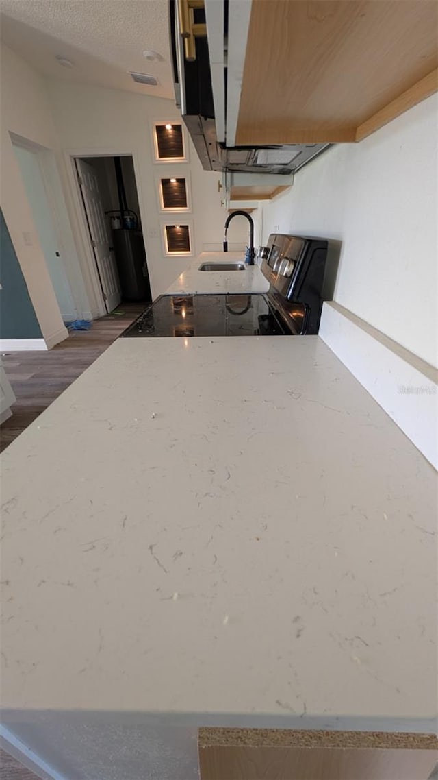 kitchen with light stone countertops, a sink, a textured ceiling, electric stove, and baseboards