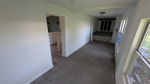 hallway with baseboards, beam ceiling, and a wealth of natural light