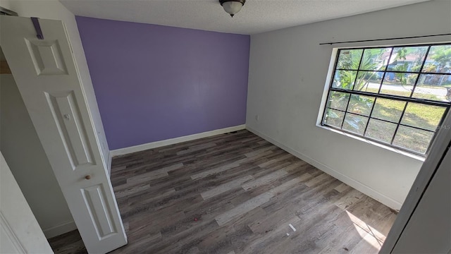 spare room featuring baseboards, a textured ceiling, and wood finished floors