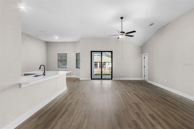 unfurnished living room with dark wood-type flooring, ceiling fan, vaulted ceiling, and sink