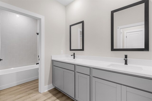 bathroom with vanity, tiled shower / bath combo, and wood-type flooring