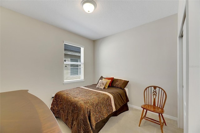 bedroom with a textured ceiling and light colored carpet