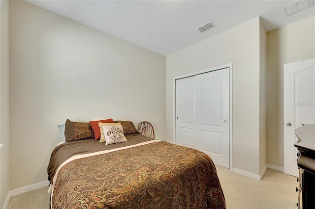 bedroom featuring light carpet, a closet, and a textured ceiling