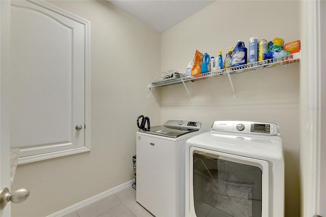 laundry room with light tile patterned flooring, washer and dryer, and a textured ceiling