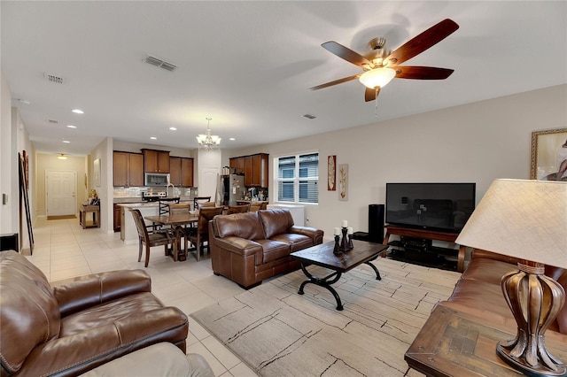 tiled living room featuring ceiling fan with notable chandelier