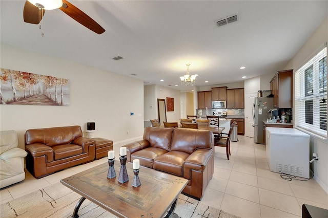 living room featuring light tile patterned flooring and ceiling fan with notable chandelier