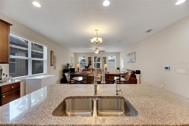 kitchen with sink, light stone counters, and ceiling fan