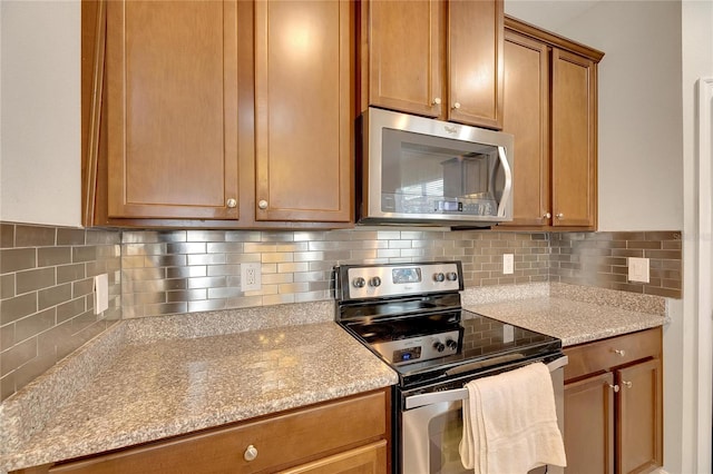 kitchen with tasteful backsplash, stainless steel appliances, and light stone countertops