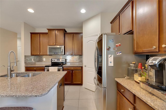 kitchen featuring light stone countertops, light tile patterned flooring, appliances with stainless steel finishes, sink, and a breakfast bar