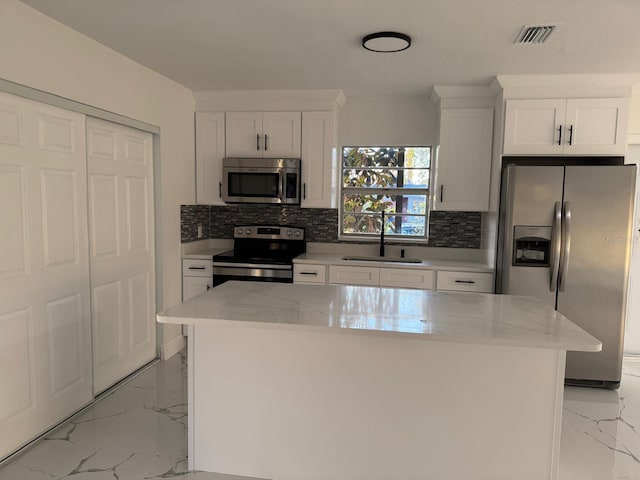 kitchen featuring light stone countertops, sink, a center island, white cabinets, and appliances with stainless steel finishes