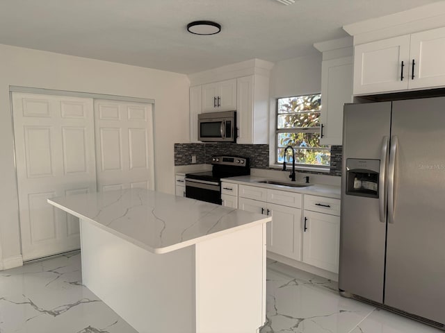 kitchen with white cabinets, a kitchen island, sink, and appliances with stainless steel finishes