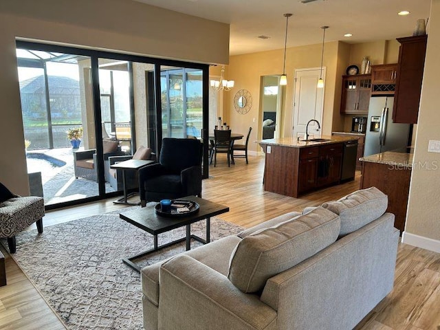 living room featuring a notable chandelier, sink, and light wood-type flooring