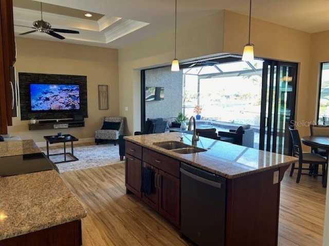 kitchen featuring dishwasher, sink, a center island with sink, and decorative light fixtures