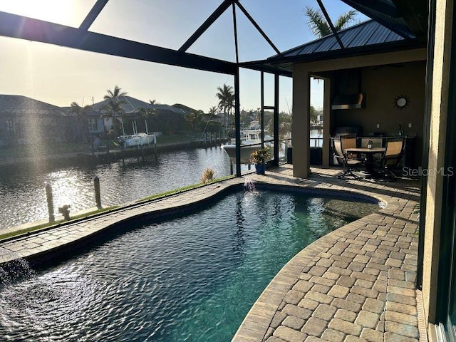 view of pool featuring a patio area, pool water feature, a water view, and glass enclosure