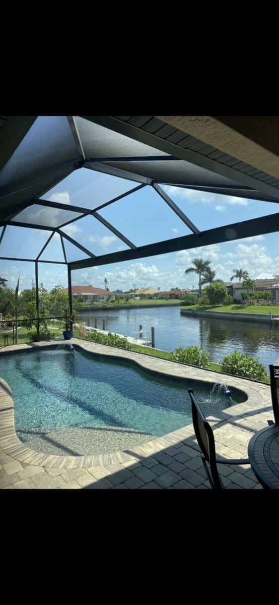 view of swimming pool with a patio area, a water view, and glass enclosure