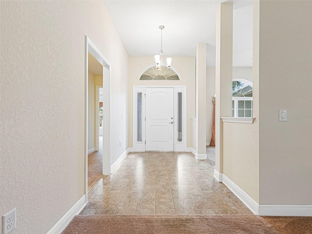 carpeted foyer entrance featuring a chandelier