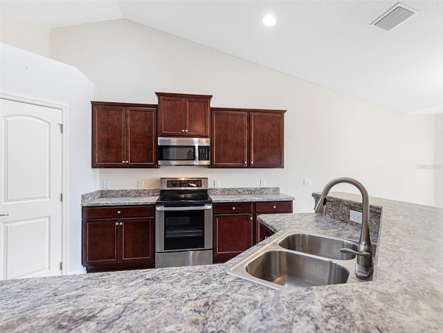 kitchen featuring lofted ceiling, dark brown cabinets, sink, and appliances with stainless steel finishes