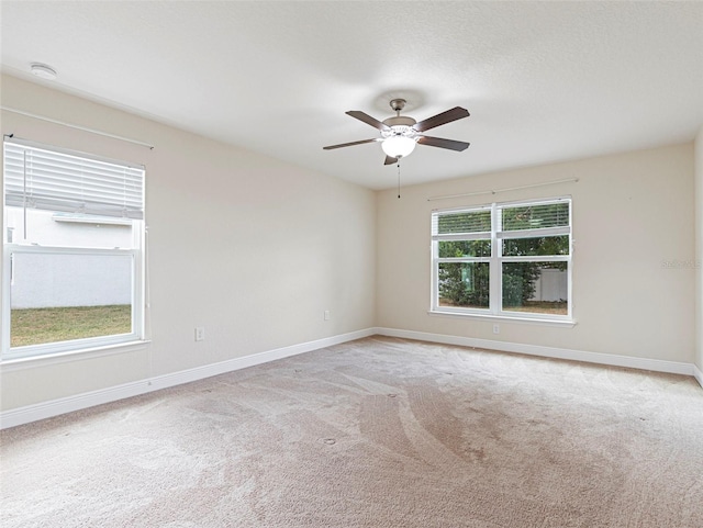 carpeted empty room featuring ceiling fan and plenty of natural light