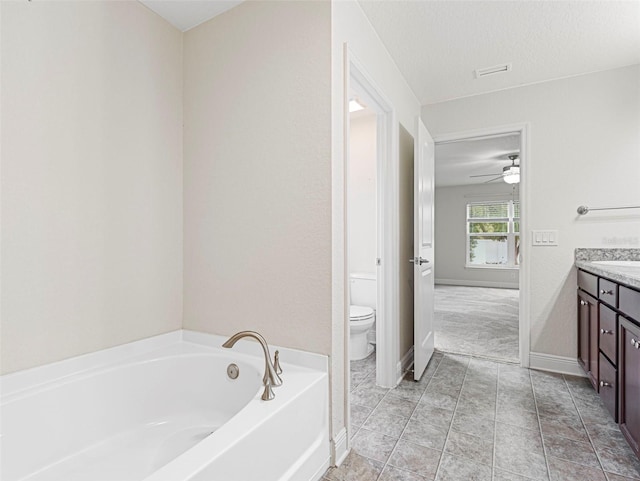 bathroom featuring a tub, ceiling fan, a textured ceiling, vanity, and toilet