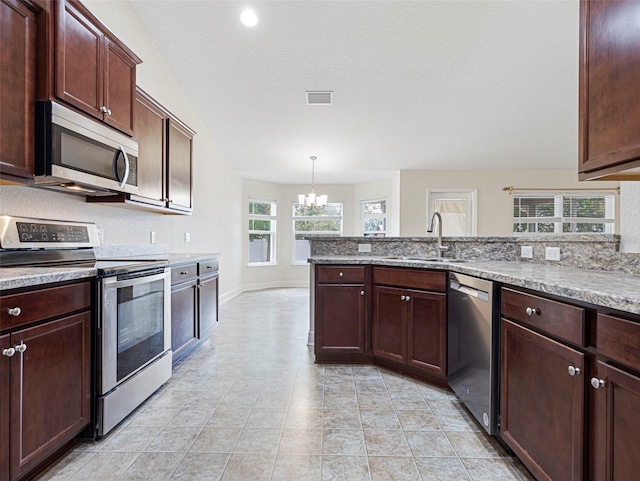 kitchen with appliances with stainless steel finishes, a notable chandelier, pendant lighting, sink, and lofted ceiling