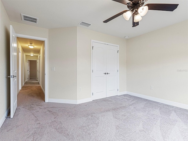 unfurnished bedroom featuring ceiling fan, light carpet, and a closet