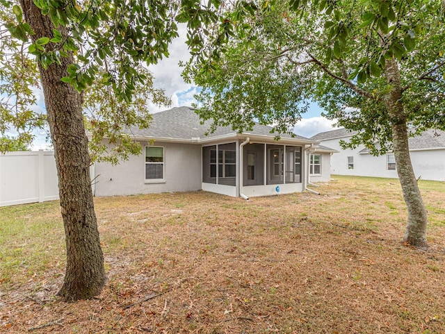 back of property with a sunroom and a lawn