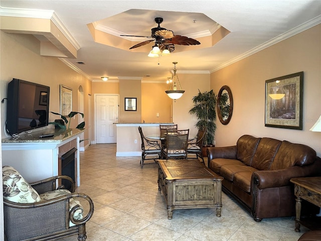 tiled living room featuring ornamental molding, ceiling fan, and a raised ceiling