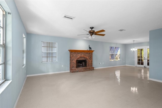 unfurnished living room with french doors, ceiling fan with notable chandelier, and a brick fireplace