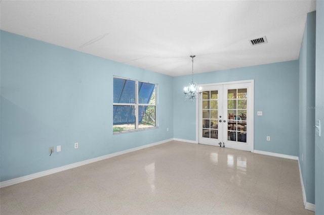 spare room featuring french doors and an inviting chandelier