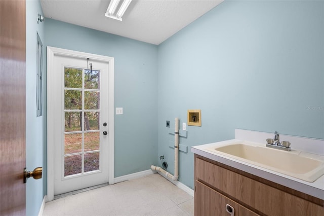 clothes washing area with hookup for an electric dryer, a textured ceiling, sink, and washer hookup