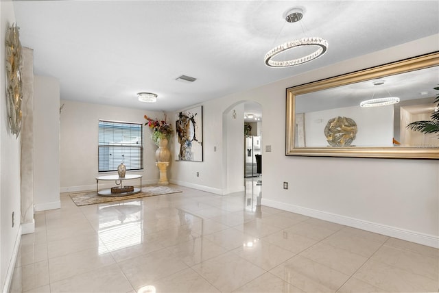 unfurnished room featuring a chandelier and light tile patterned floors