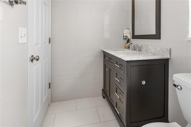 bathroom with tile walls, tile patterned flooring, vanity, and toilet