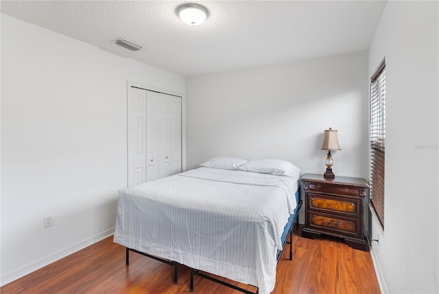 bedroom with a closet, wood-type flooring, and a textured ceiling