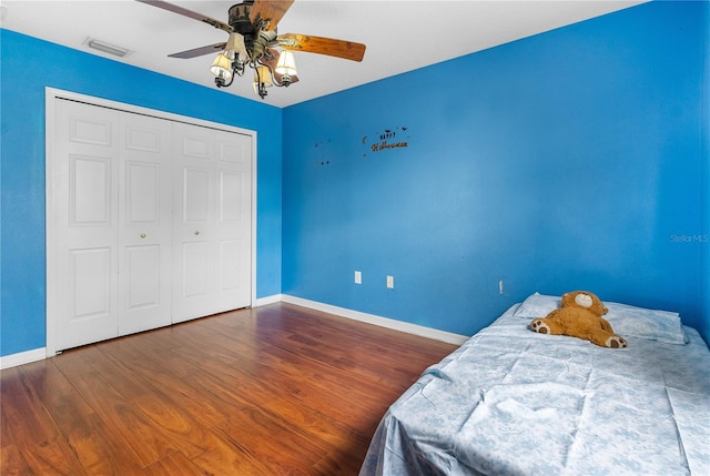 bedroom with dark wood-type flooring, a closet, and ceiling fan