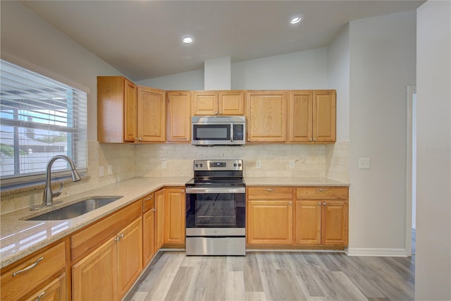 kitchen with decorative backsplash, stainless steel appliances, sink, light hardwood / wood-style flooring, and lofted ceiling