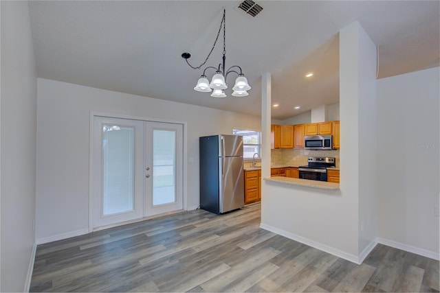 kitchen featuring decorative light fixtures, light hardwood / wood-style floors, appliances with stainless steel finishes, and an inviting chandelier