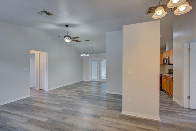 unfurnished living room featuring ceiling fan with notable chandelier, french doors, and light hardwood / wood-style flooring