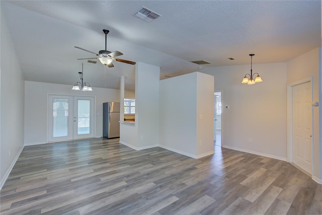 unfurnished living room featuring a textured ceiling, french doors, ceiling fan with notable chandelier, and light wood-type flooring