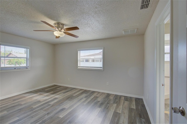 spare room with plenty of natural light, wood-type flooring, and a textured ceiling