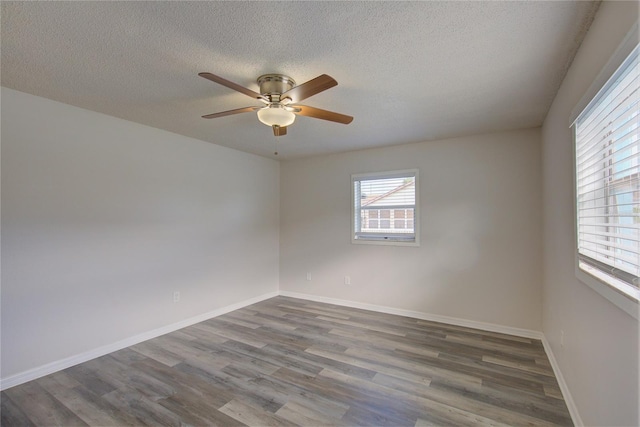 empty room featuring ceiling fan, dark wood-type flooring, and a textured ceiling