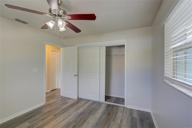 unfurnished bedroom featuring ceiling fan, dark hardwood / wood-style flooring, a textured ceiling, and a closet