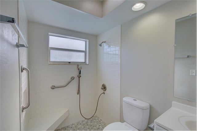 bathroom featuring a tile shower, vanity, and toilet