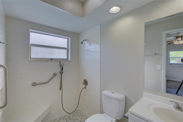 bathroom with vanity, ceiling fan, toilet, and tiled shower