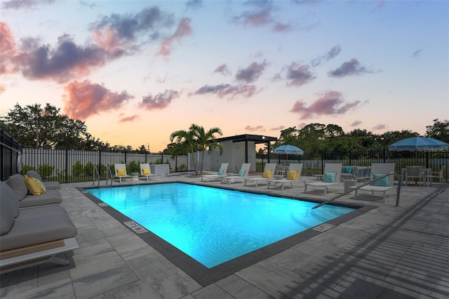 pool at dusk featuring a patio