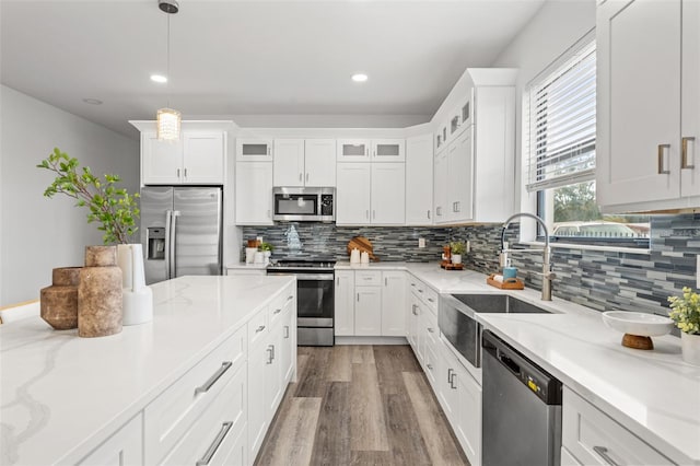 kitchen featuring pendant lighting, white cabinetry, light hardwood / wood-style flooring, and stainless steel appliances