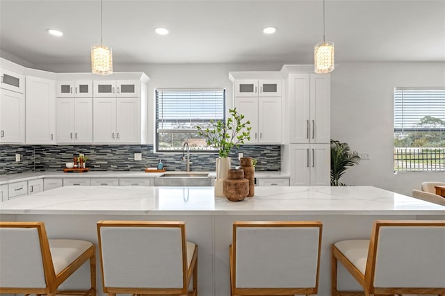 kitchen featuring a kitchen breakfast bar, decorative light fixtures, white cabinets, and sink